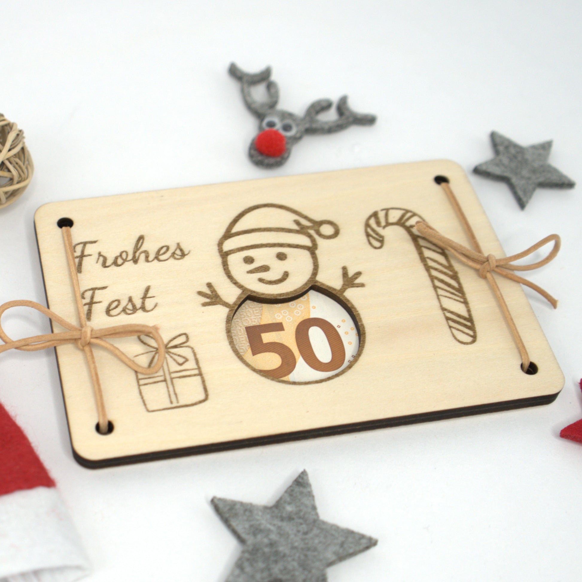 Geldgeschenk aus Holz mit Schneemann-Design und Lederbändern – weihnachtlich dekoriert
