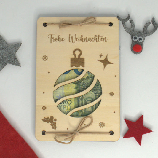 Holz-Geldgeschenk zu Weihnachten mit Gravur ‚Frohe Weihnachten‘ und ausgelaserter Weihnachtskugel, dekoriert mit Geldschein.