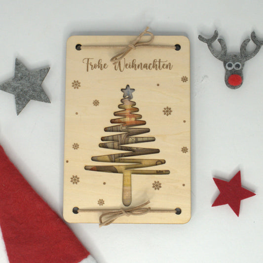Geldgeschenk aus Holz mit ausgeschnittenem Tannenbaum und Frohe-Weihnachten-Gravur – dekorative Karte für Geldscheine.