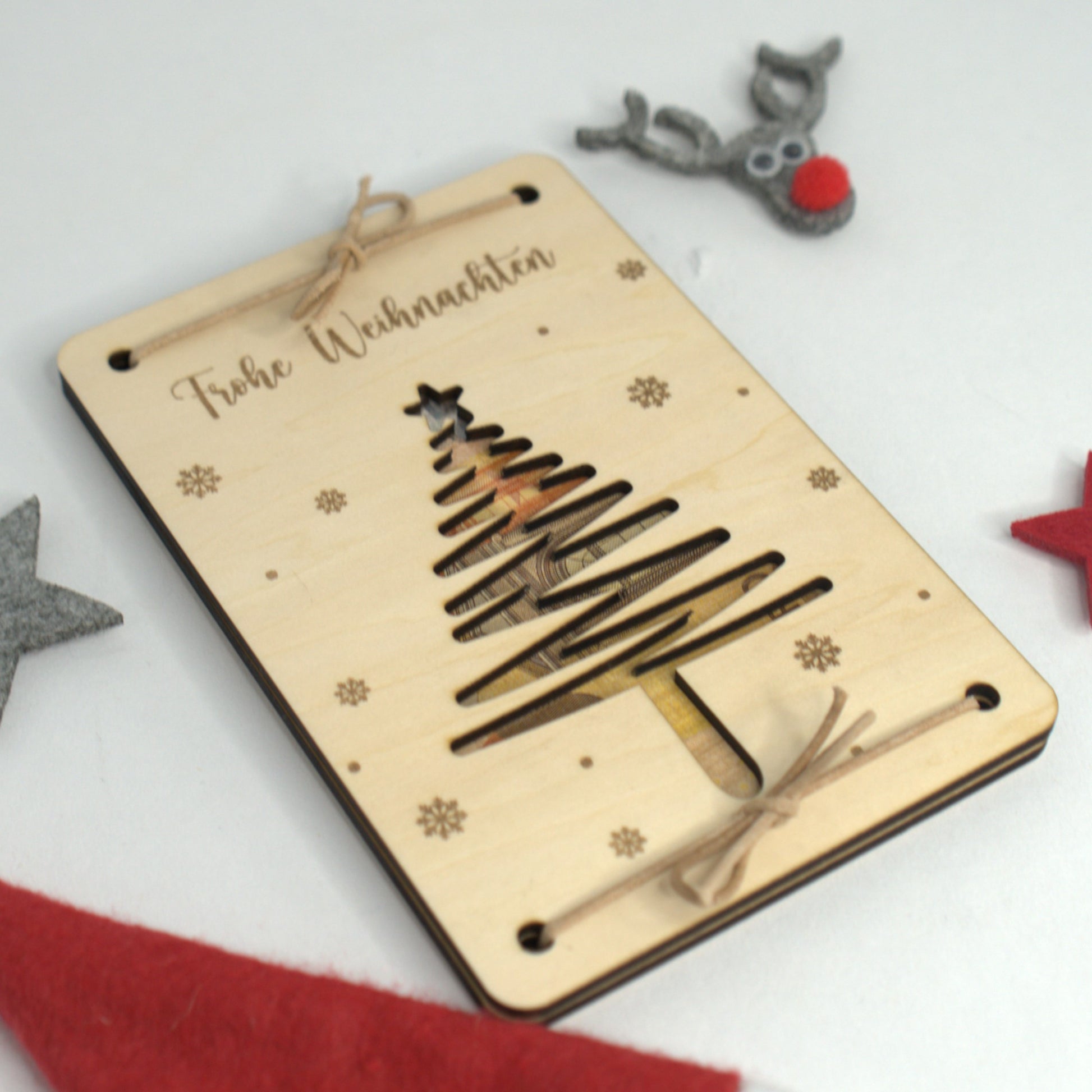 Weihnachtliches Geldgeschenk aus Holz, Tannenbaum-Ausschnitt, Schneeflocken graviert, dekorativ arrangiert.