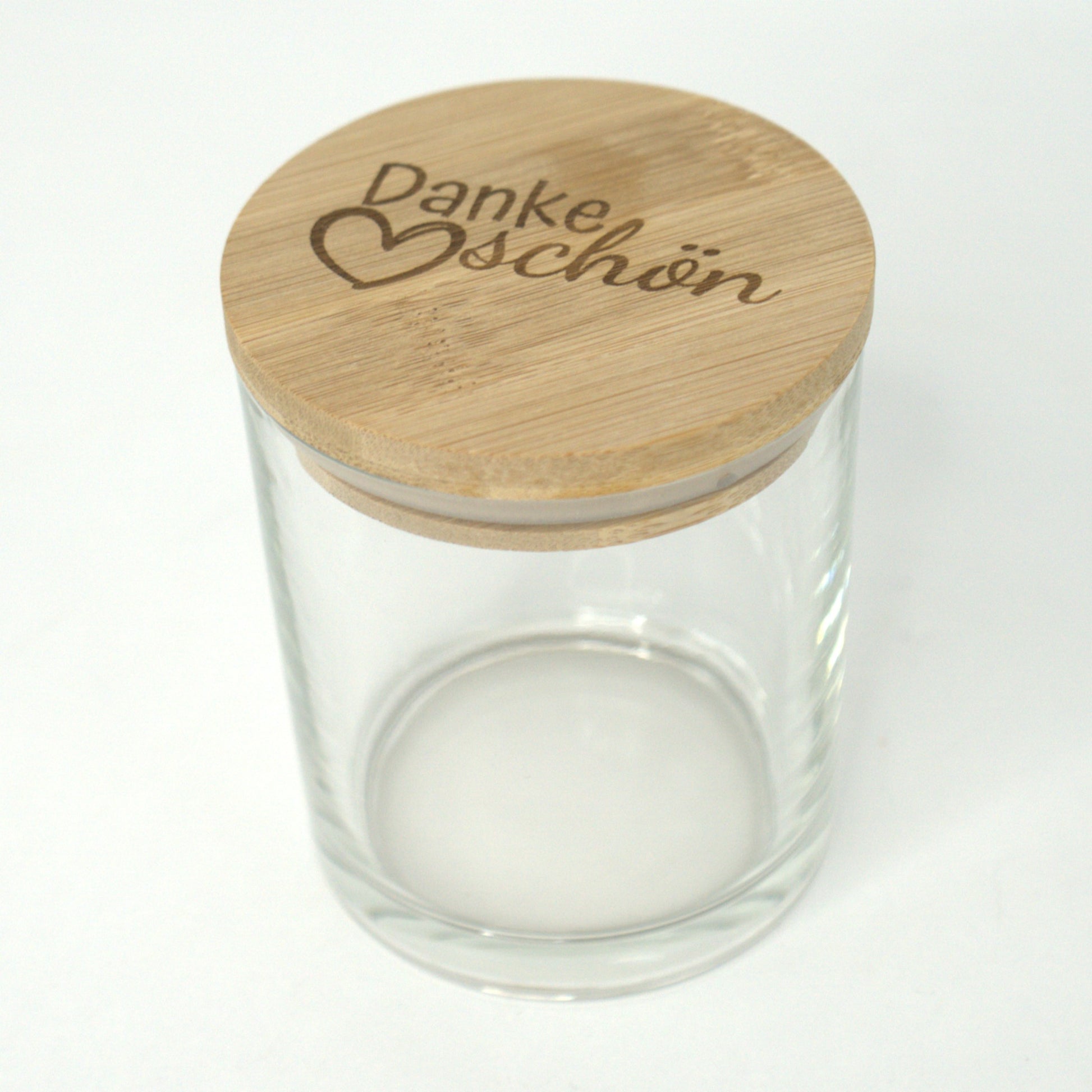 Leeres Glas und abgelegter Bambusdeckel mit Gravur ‚Dankeschön‘