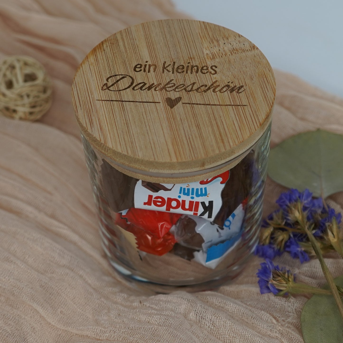 Geschenkglas mit graviertem Bambusdeckel „Ein kleines Dankeschön“ gefüllt mit Süßigkeiten, dekorativ arrangiert.