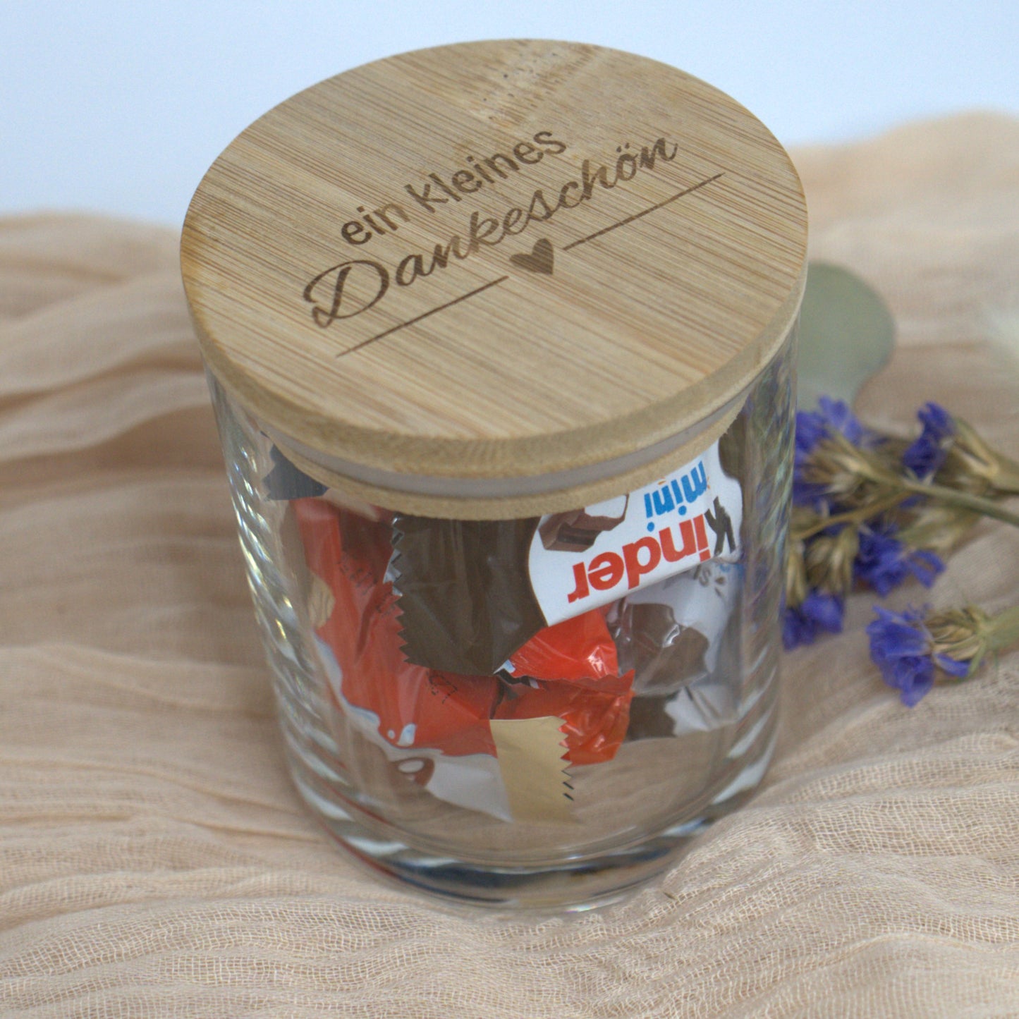Detailaufnahme des Dankeschön-Glases mit Bambusdeckel und Süßigkeitenfüllung auf Stoffuntergrund.