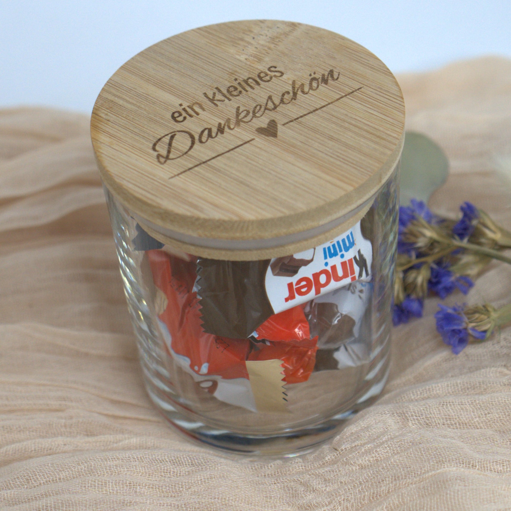 Detailaufnahme des Dankeschön-Glases mit Bambusdeckel und Süßigkeitenfüllung auf Stoffuntergrund.