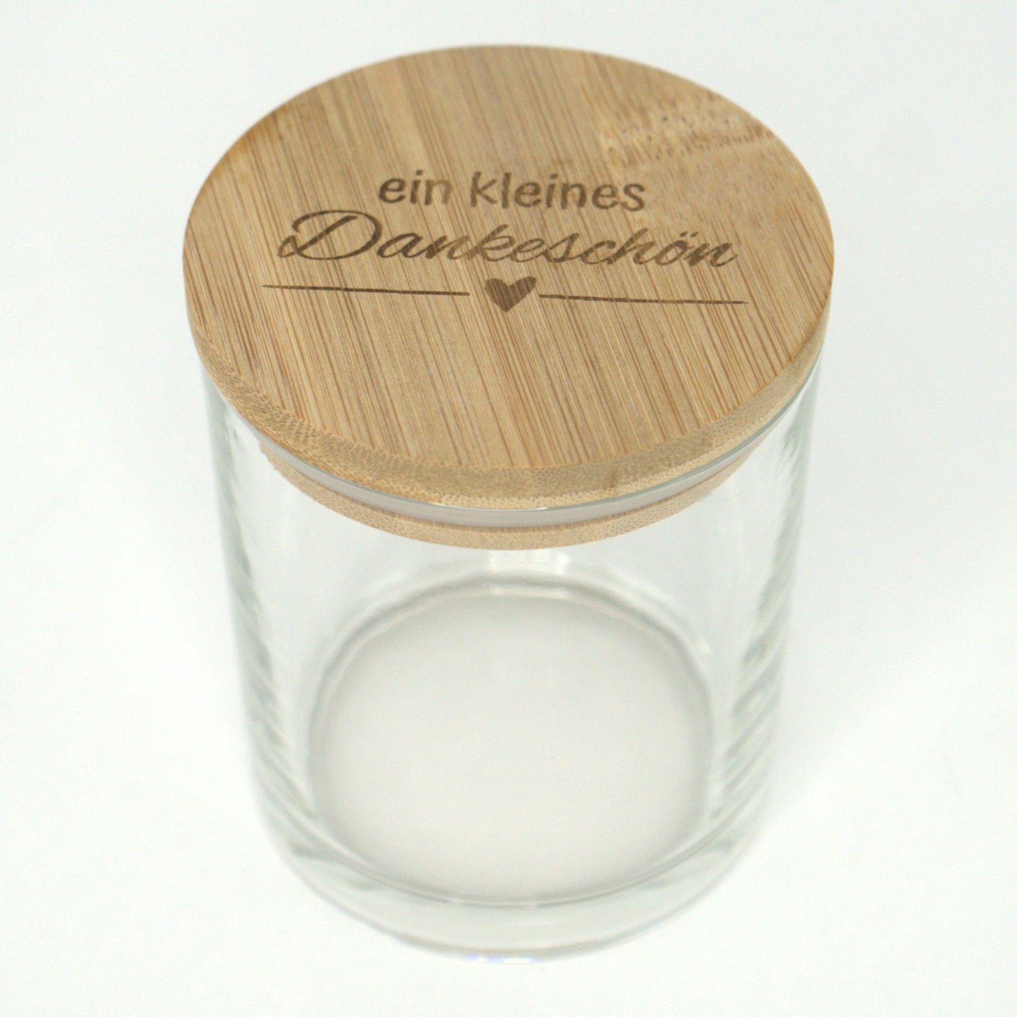 Leeres Glas mit graviertem Bambusdeckel „Ein kleines Dankeschön“ leicht von oben fotografiert.