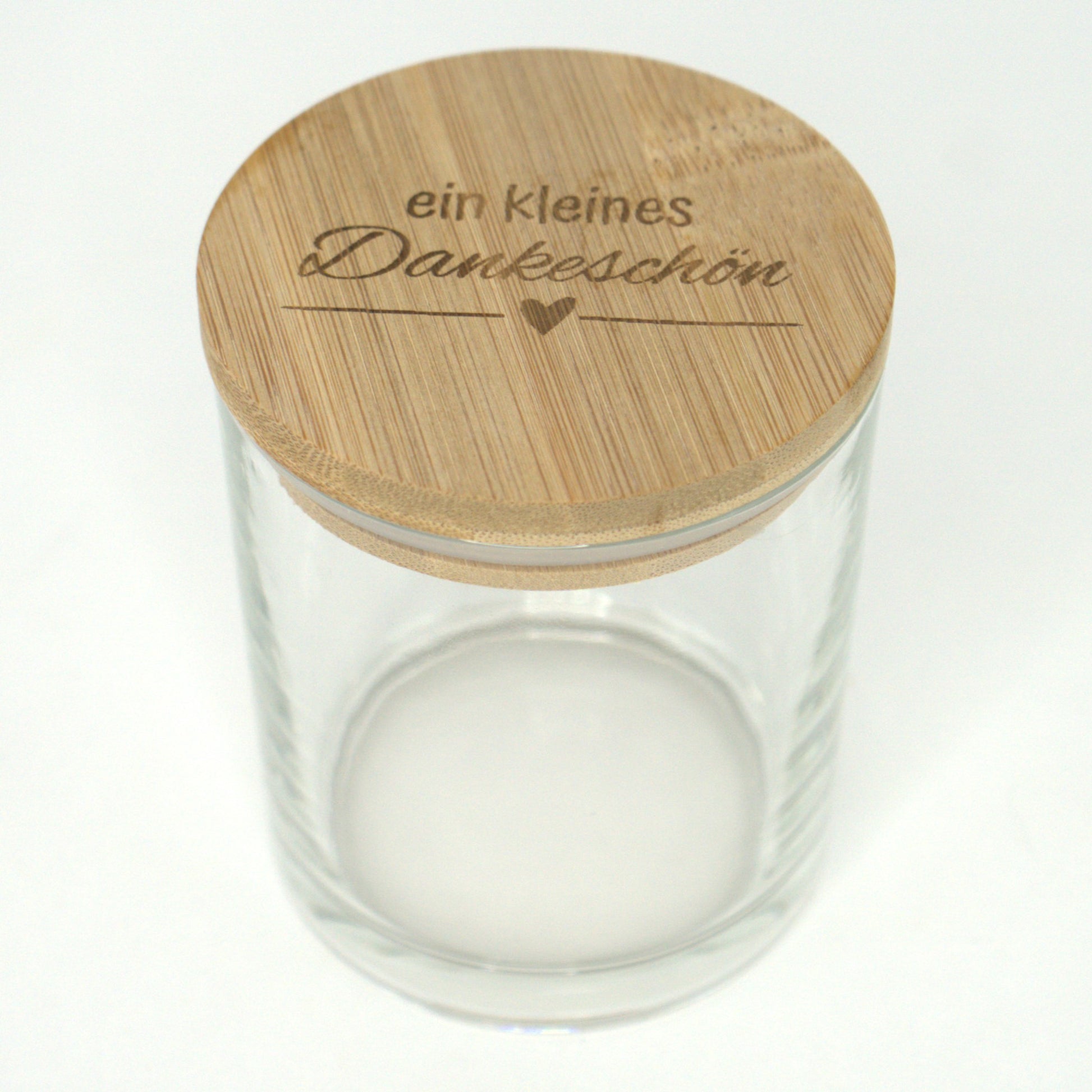 Leeres Glas mit graviertem Bambusdeckel „Ein kleines Dankeschön“ leicht von oben fotografiert.